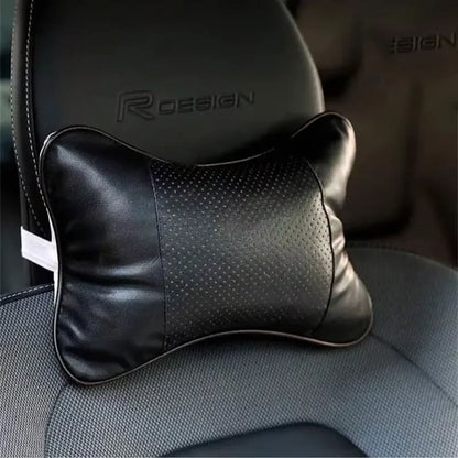 Coussin cervical haut de gamme en cuir noir avec zone centrale perforée, installé sur un siège auto en cuir.