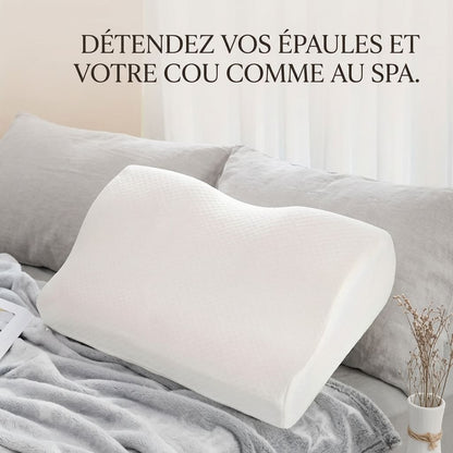 Oreiller ergonomique à mémoire de forme blanc posé sur un lit pour la détente du cou et des épaules