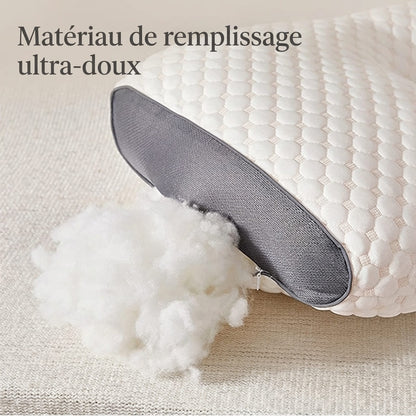 Gros plan sur le matériau de remplissage ultra-doux en fibres blanches sortant d'un oreiller cervical bicolore pour illustrer le moelleux et la qualité du rembourrage.